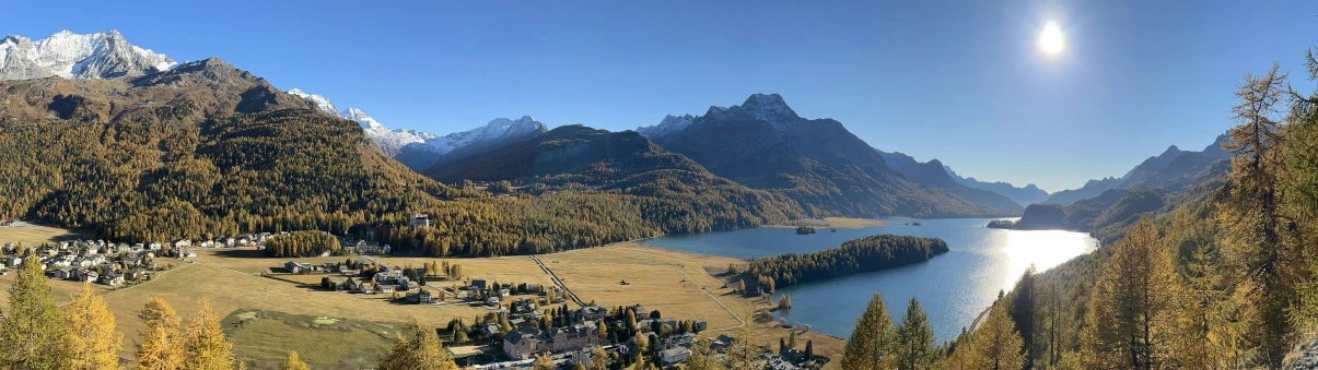 sun over a mountain range with the body of water between the mountains