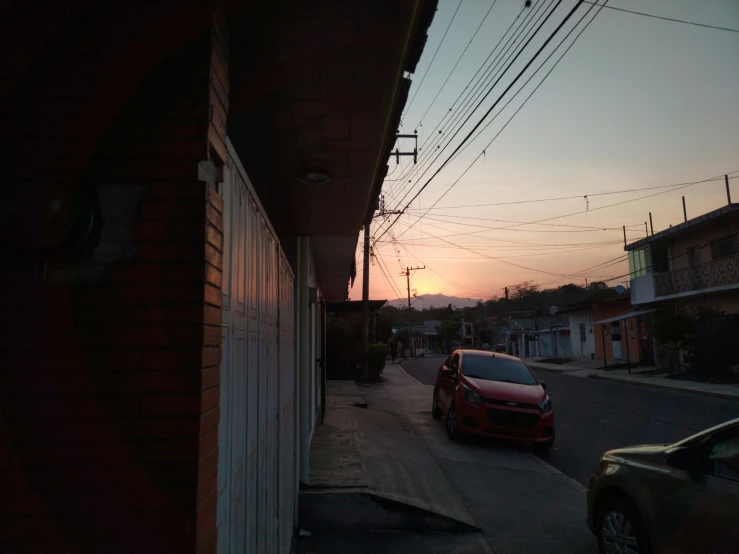 a red car parked in front of a garage next to a building