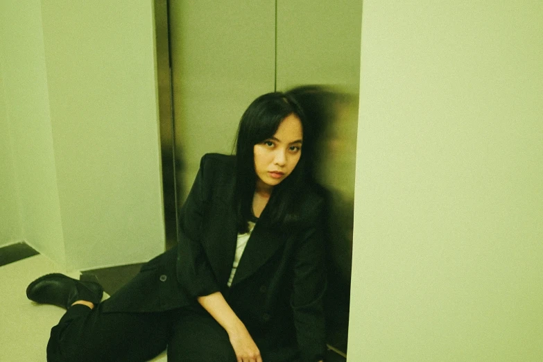 a woman wearing black and sits on a bathroom floor