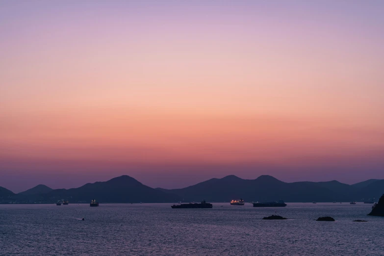 the boats are sailing in the ocean at dusk