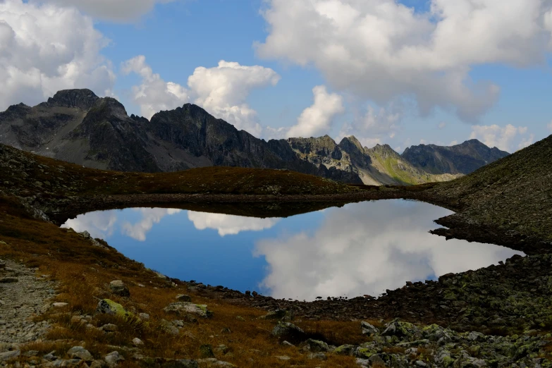 mountains and clouds reflect in the water as seen from the hillside