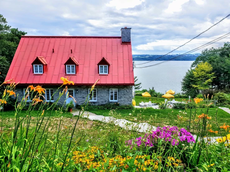 a red roof sits on the side of a house near water