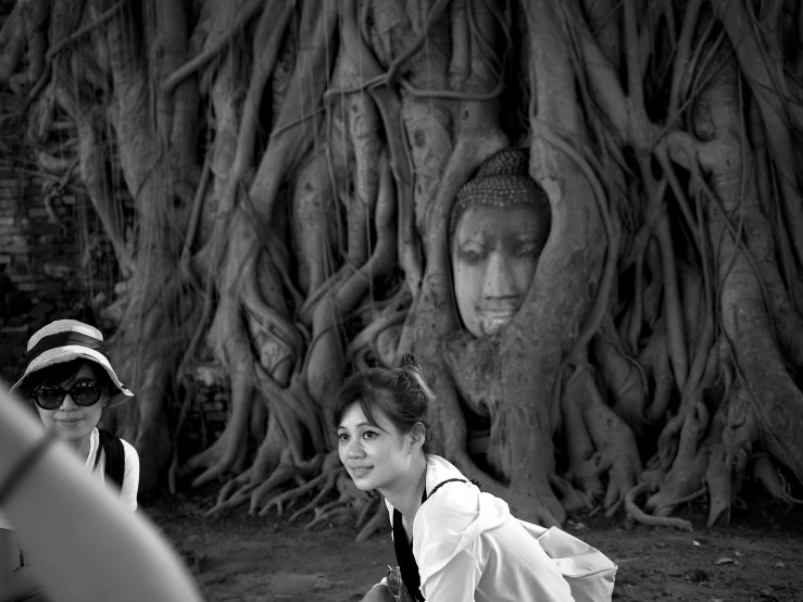 a woman walking past an old tree with its roots twisted