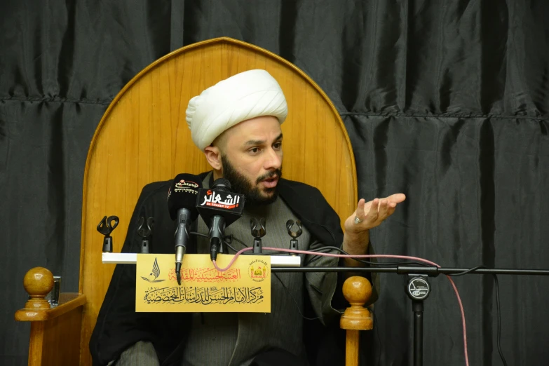 a man with a white turban speaks into microphones