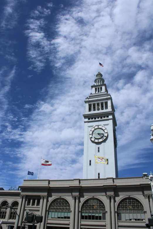 a tall white clock tower with a flag on top