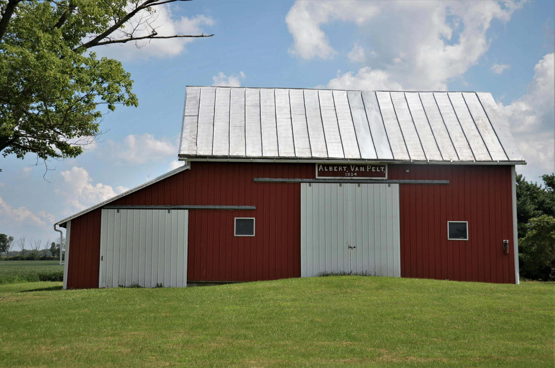 a red barn in the country with two wind turbine doors