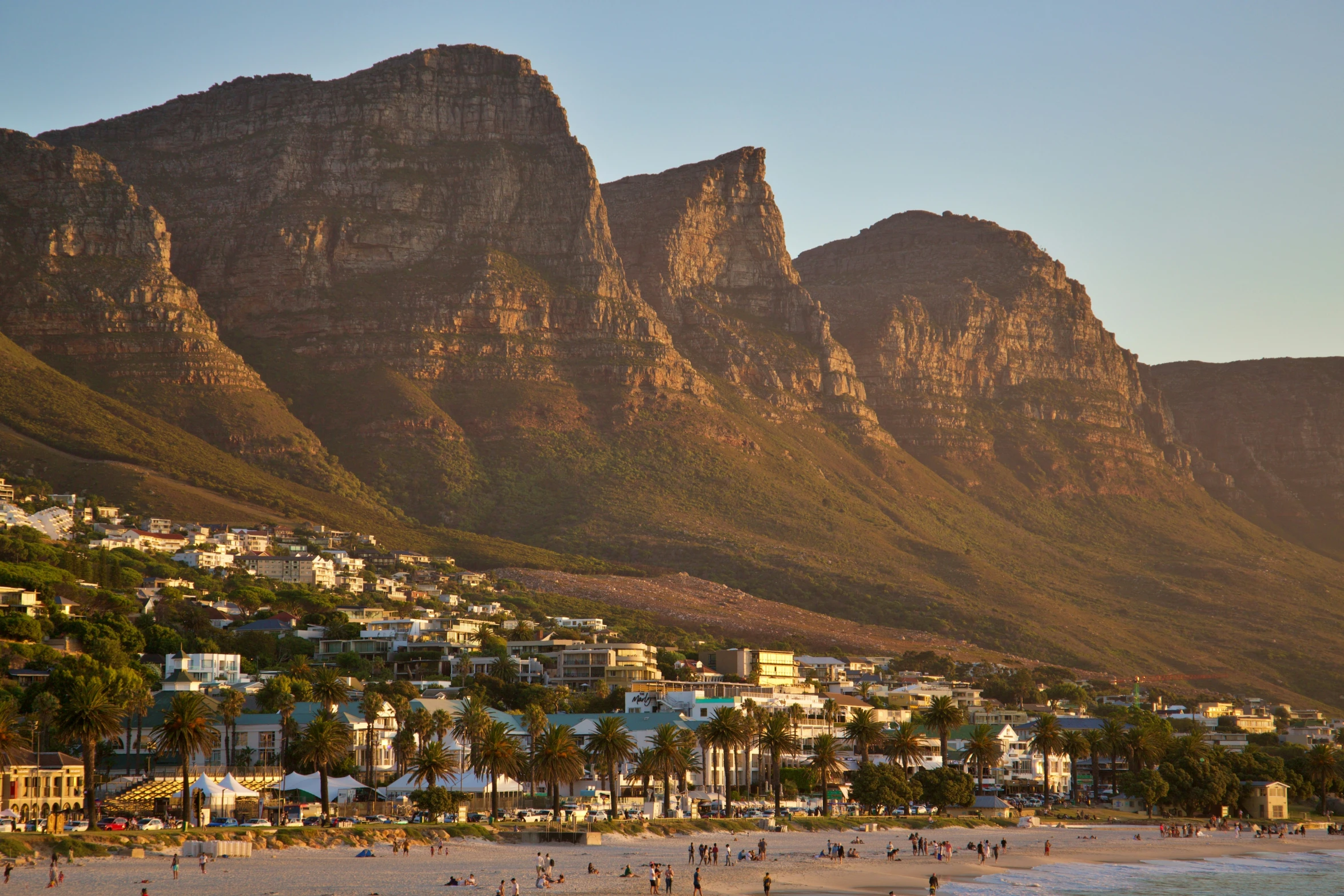 people at the beach in front of a mountain