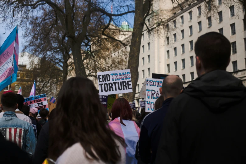 people at a protest holding signs and standing in front of a building