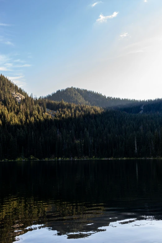 the sun sets on the mountain and trees reflected in water