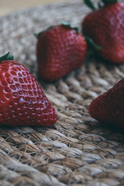 several strawberries sit on top of a woven basket