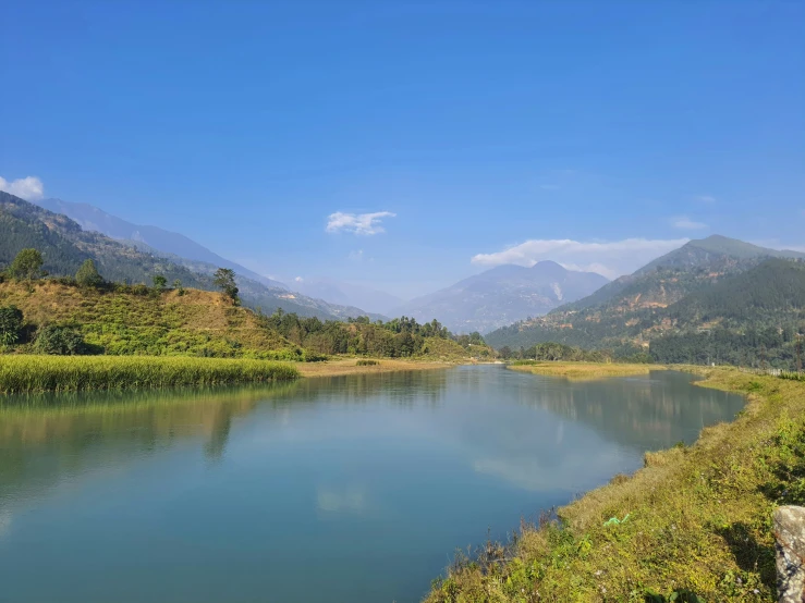 the view of mountains, a body of water, and green plants