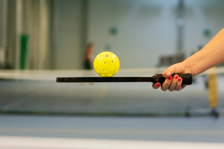 a woman is trying to lift a yellow ball with a black handle