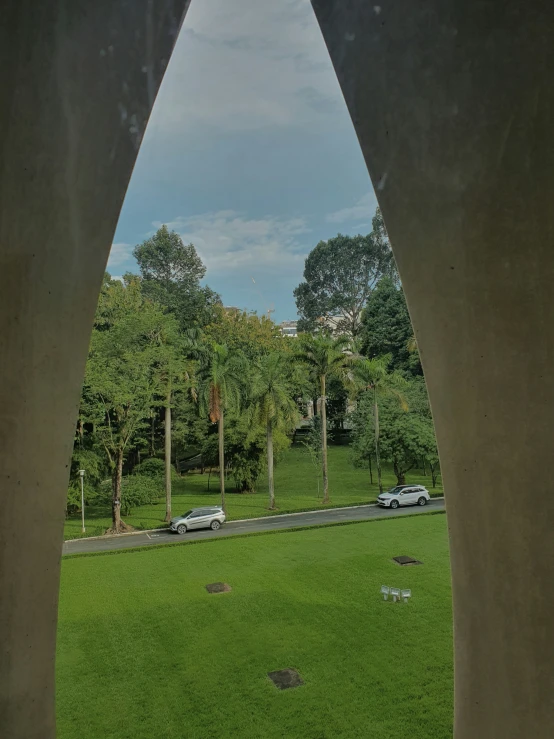 a grassy area with cars seen through a portal in it