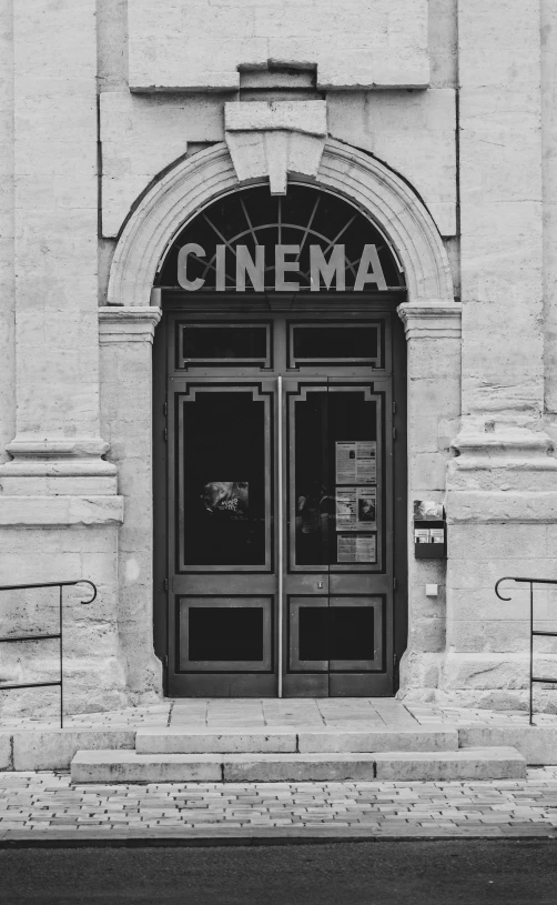 a vintage black and white s of a cinema sign above a doorway