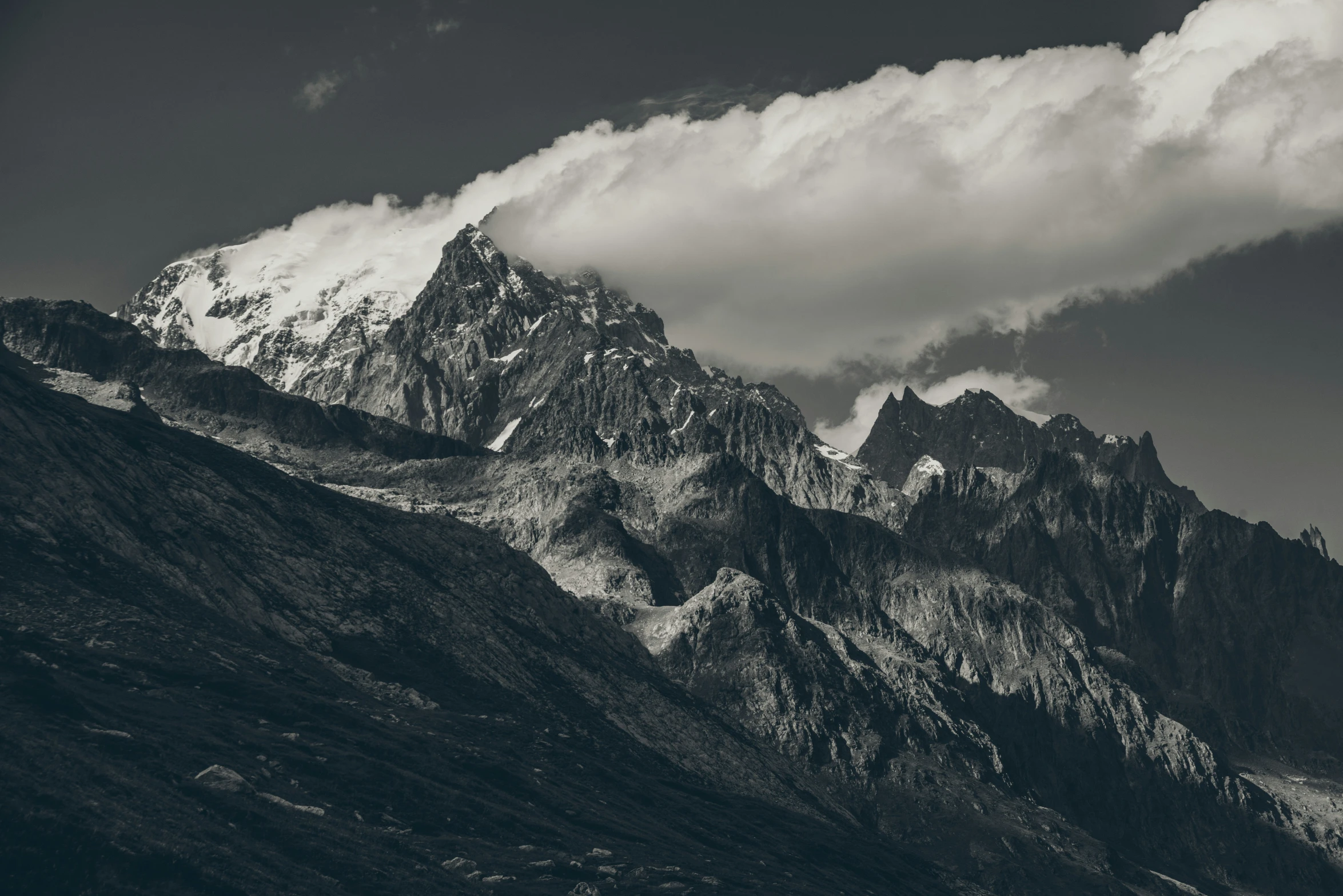 a mountain side with a few clouds hanging from it