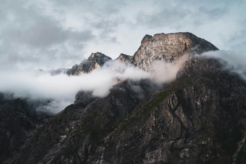 the top of a mountain is seen through clouds