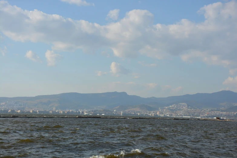 a kite in the air over water with mountains in the background