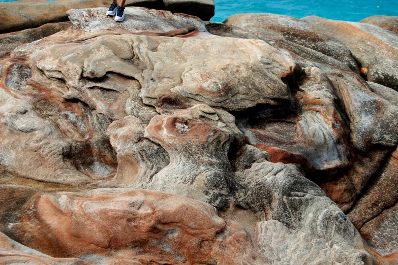 a person stands on top of a rock in front of a body of water