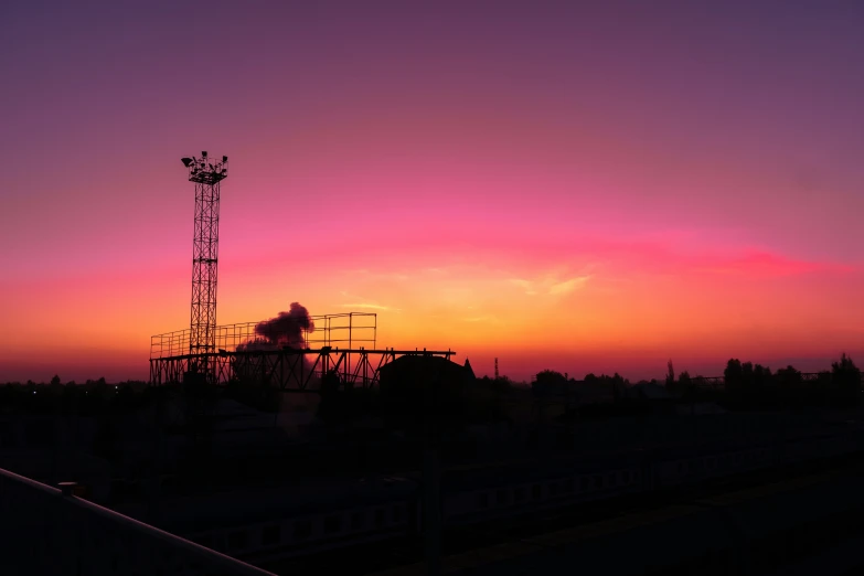 a silhouette of a cell tower against the sun