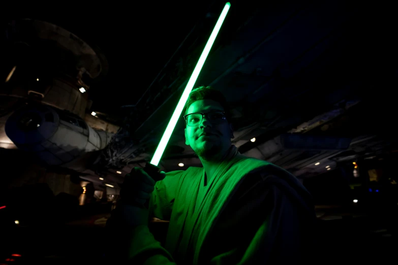 a man standing with lightsabed against a dark background