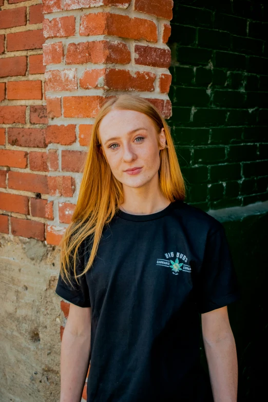 a woman with red hair posing in front of a brick wall