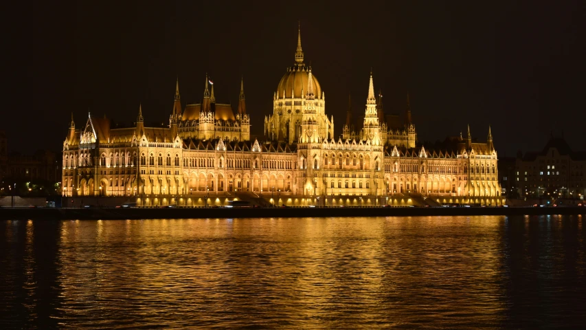 a castle with clock at night from across the water