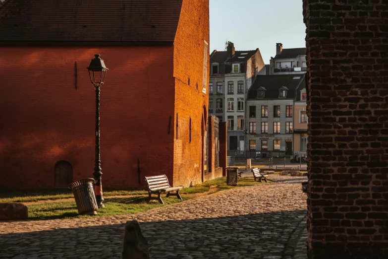 a road between two buildings and benches along side it