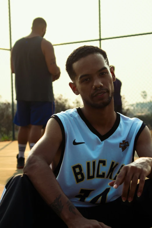 young man sitting in front of basketball court looking concerned