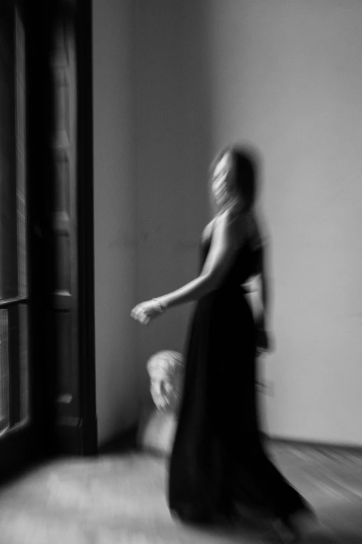 black and white po of woman in long dress in the hallway
