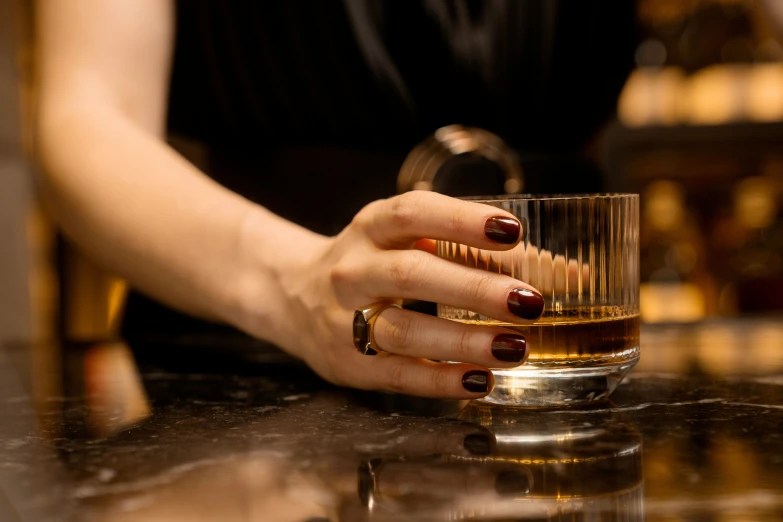 a woman with red manicured nails sitting in front of a cup