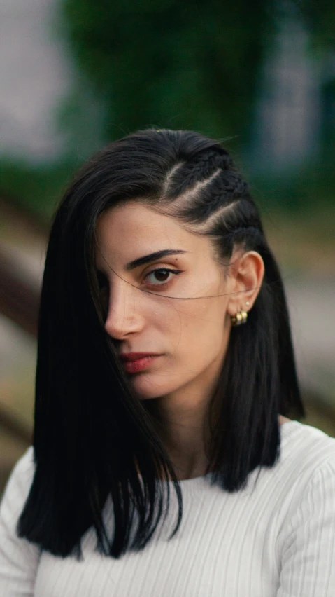 a woman with very long black hair wearing large ear studs