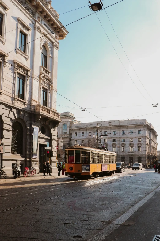 an orange trolley car drives down a very narrow street