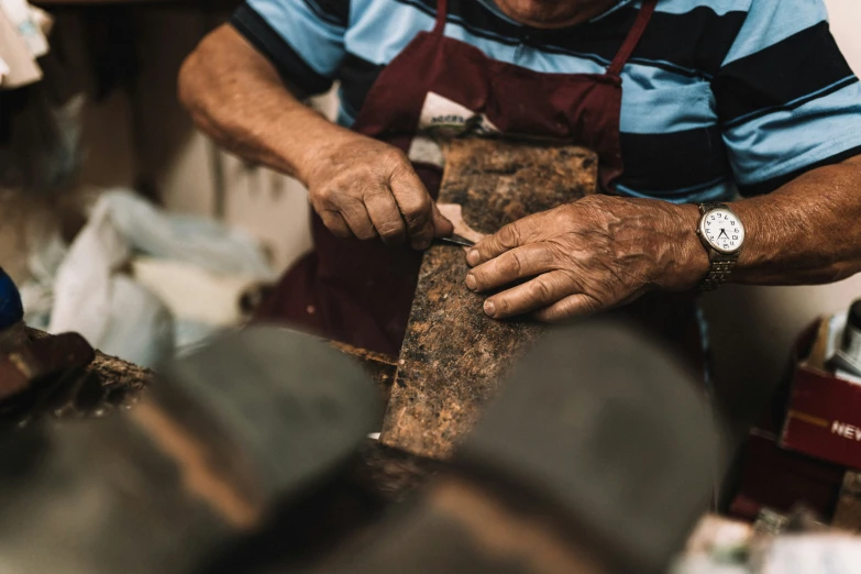 a man wearing an apron working on a piece of wood