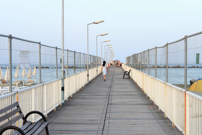 a group of people walking along a long bridge next to the ocean