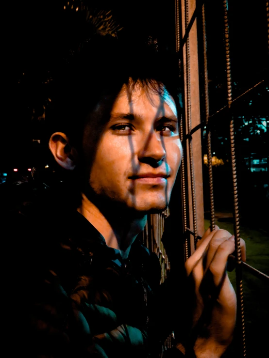 a man standing next to a fence outside