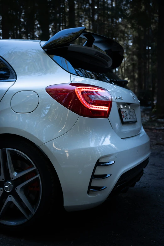 a white car with some black tires sitting in front of trees