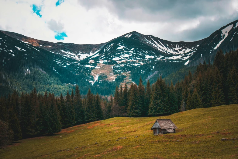 a house sits on a hillside in front of a mountain