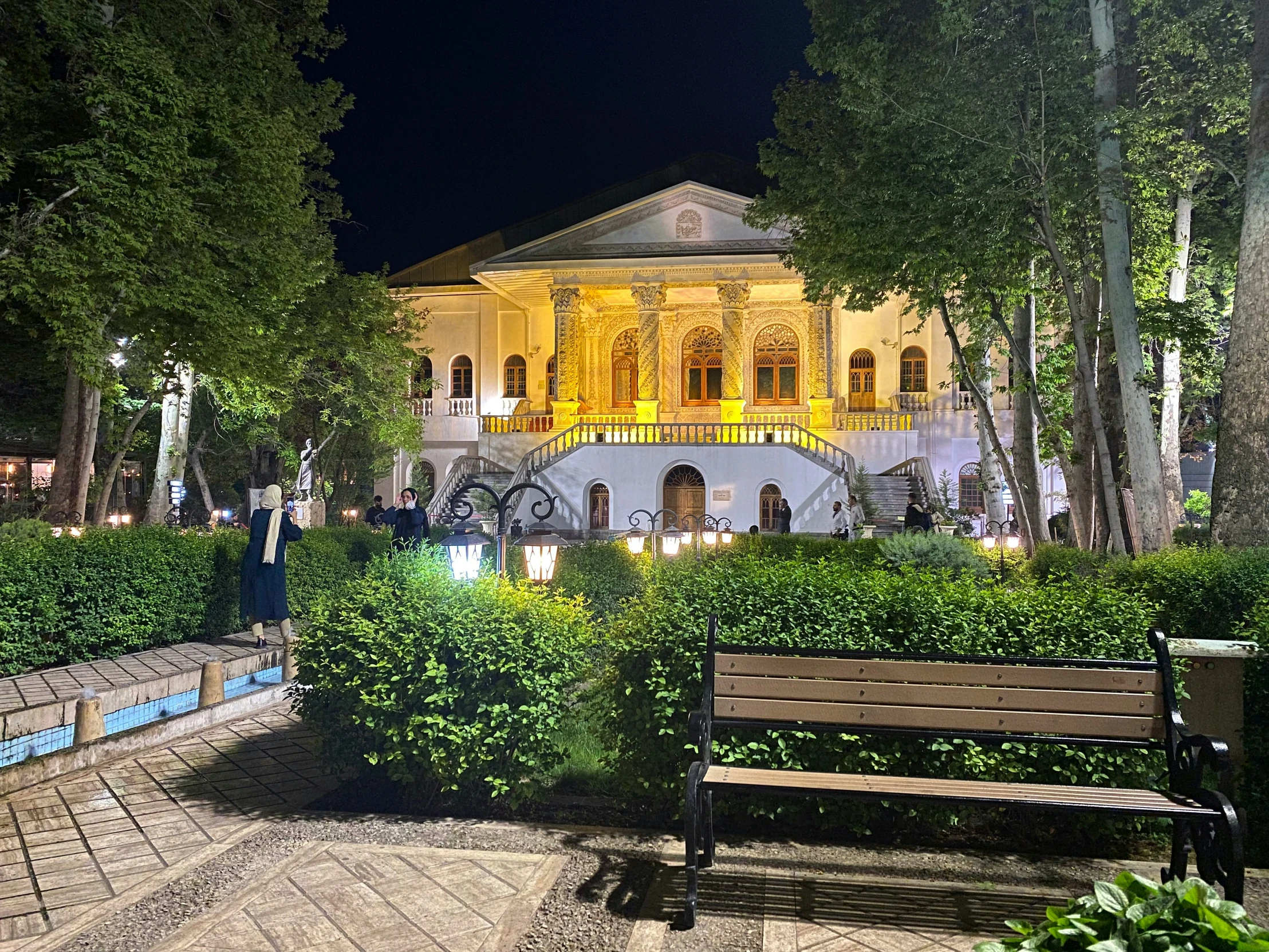 night view of a building surrounded by green bushes