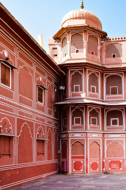 a building with a large clock and balcony is pink with white architecture