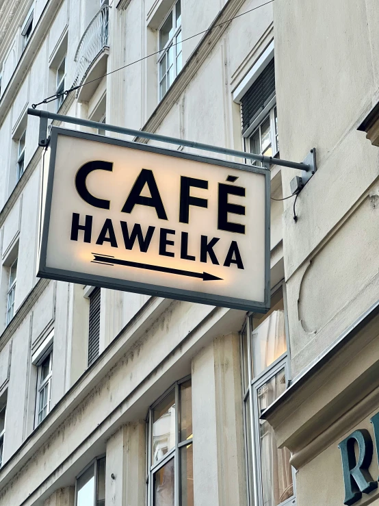 a cafe sign hanging outside of a building