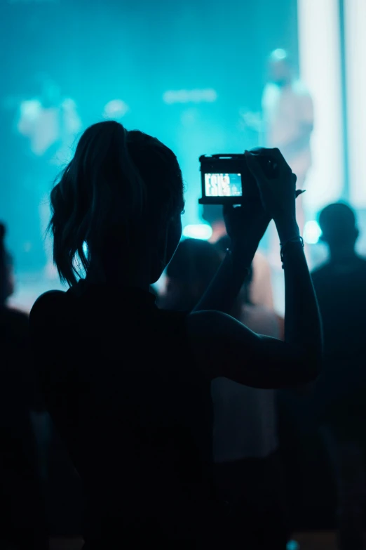 a woman is taking a po with her phone at a concert
