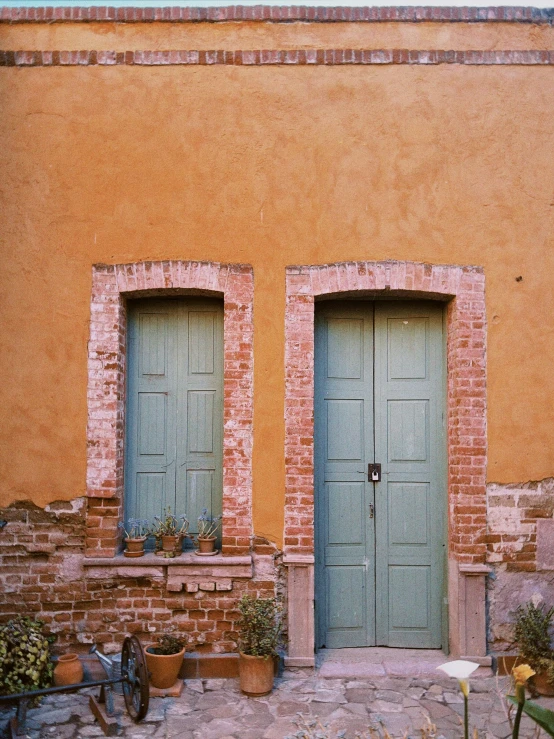 two green doors that are next to a brick building