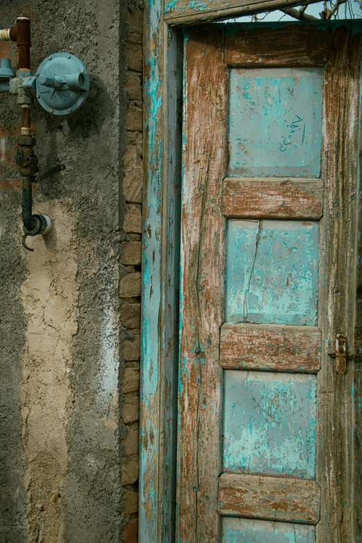 an old dirty door sitting next to a water spigot