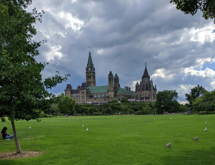 a large building with two tall towers sits on top of a lush green field