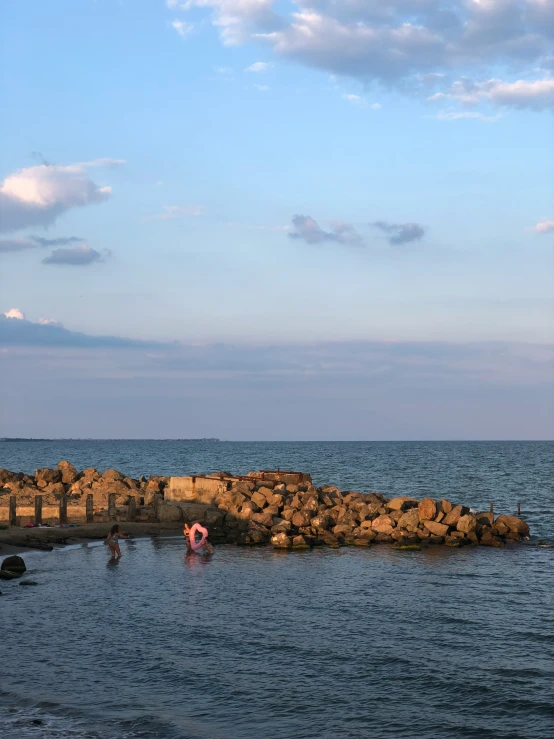 people are in the water near a breakwater