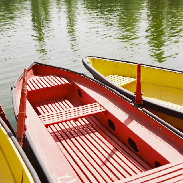 a row boat sits on the water next to two smaller ones