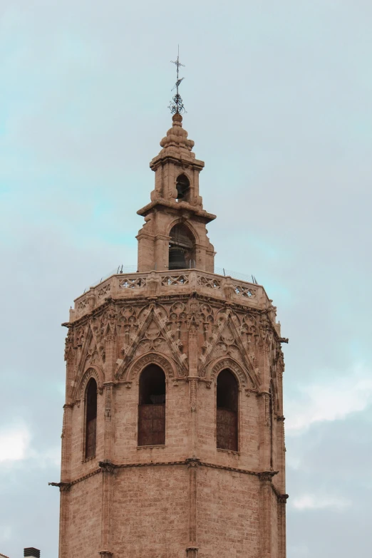 a clock tower with an ornate top and a cross at the top