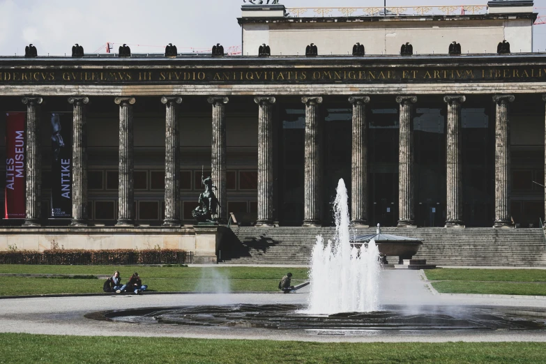 a fountain with people around in front of a building