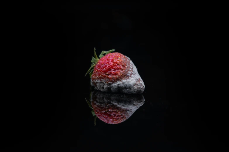 strawberry on black reflective surface with reflection