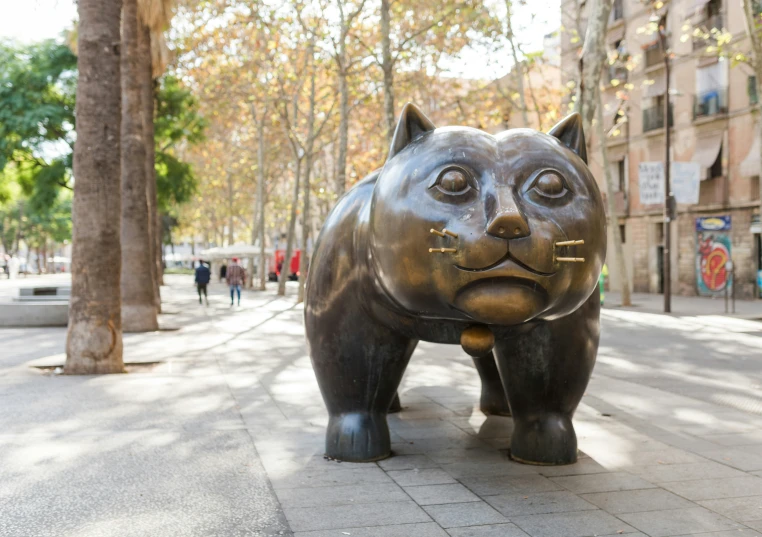 a sculpture of a cat walking on the sidewalk